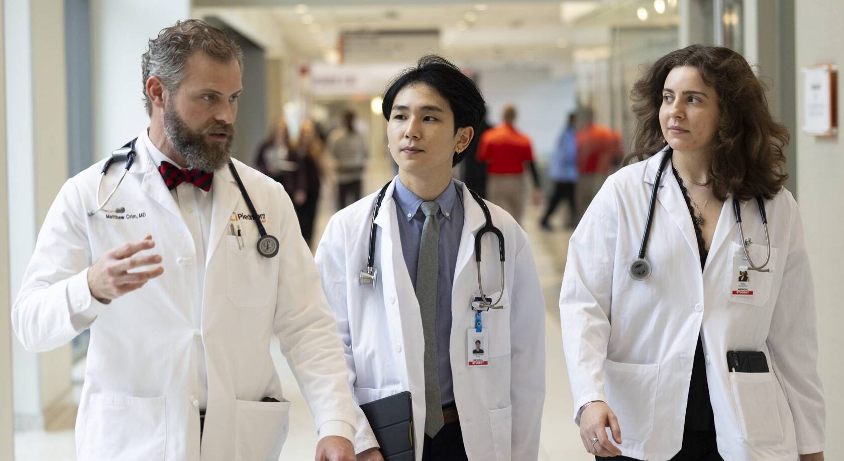 Two students from the University of Georgia School of Medicine speak with a doctor as they walk the halls of a hospital