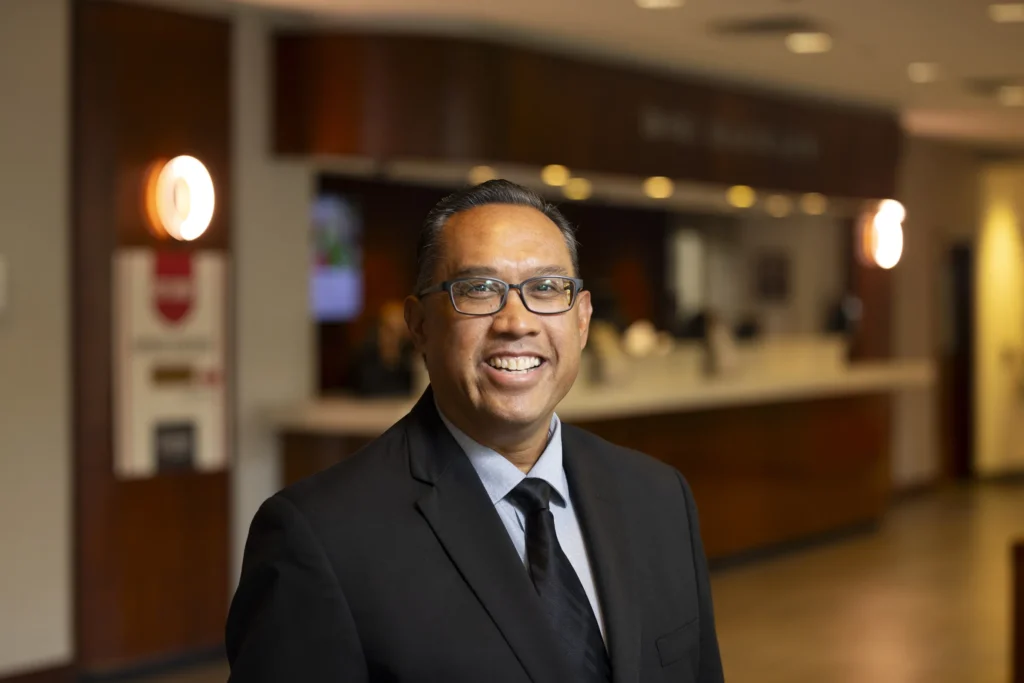 Professor John Salazar from the University of Georgia is wearing a dark suit and smiling at the camera for a profile photo.